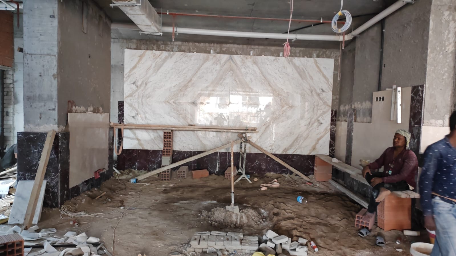 A craftsman carefully installing a large marble tile on a wall.